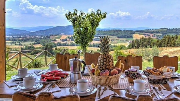 A table set for breakfast with a scenic view of rolling hills and a clear sky. - Villa Morotti Comfortable Holiday Residence (Montone)