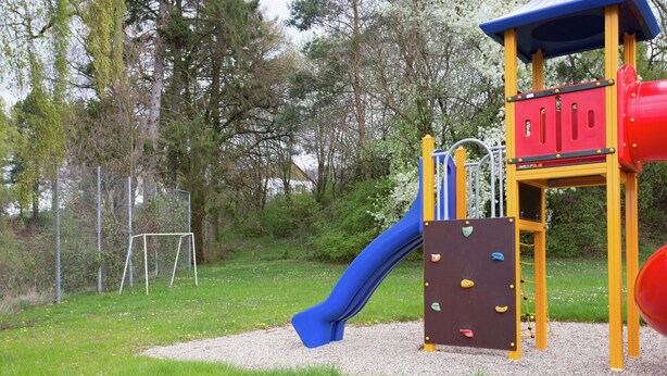 A playground with a slide, climbing wall, and a red and yellow play structure.