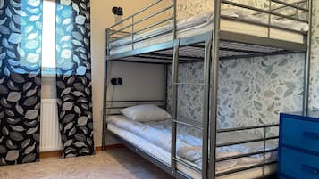 A bunk bed room with a patterned curtain, a radiator, and a blue dresser.