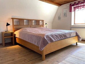 A bedroom with a wooden bed, two bedside lamps, a small nightstand, and a window with curtains. - 5 Person Holiday Home in Ulrika-by Traum (Ulrika)
