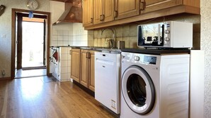 A kitchen with wooden cabinets, a washing machine, a microwave, and a sink. - 5 Person Holiday Home in Ulrika (Ulrika)