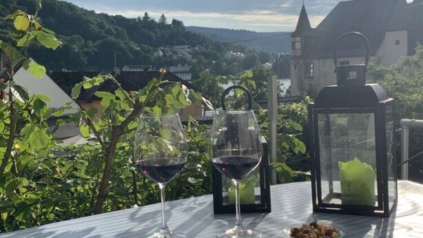 A table with two wine glasses and a lantern on a terrace overlooking a scenic landscape. - Holiday Apartment by the Pond (Kamp-Bornhofen)