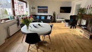 A modern living room with a round dining table, a sofa, and a TV. - Holiday Apartment by the Pond (Kamp-Bornhofen)
