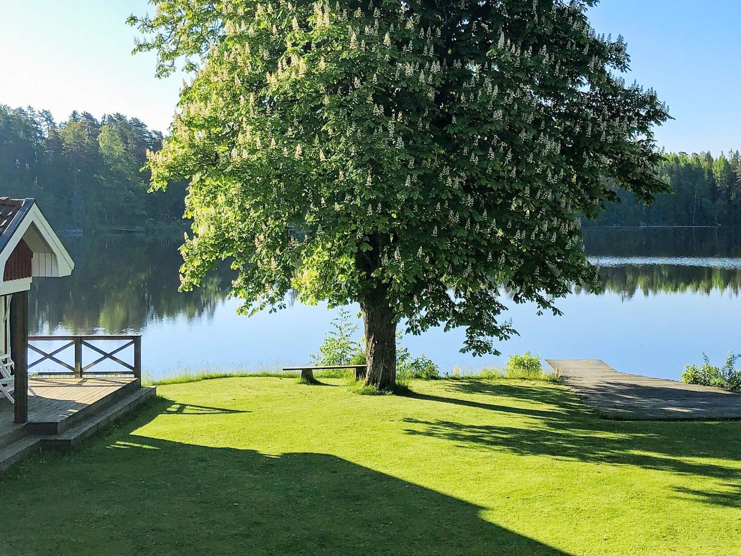 A lakeside property with a wooden dock, a small pavilion, and a large tree providing shade.