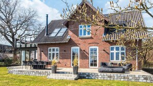 A two-story brick house with a tiled roof, a patio with outdoor furniture, and a chimney. - 8 Person Holiday Home in Bjert (Bjert)