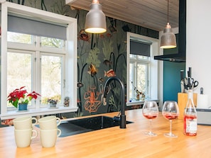 A kitchen with a black faucet, wooden countertop, and two hanging pendant lights. - 8 Person Holiday Home in Bjert (Bjert)