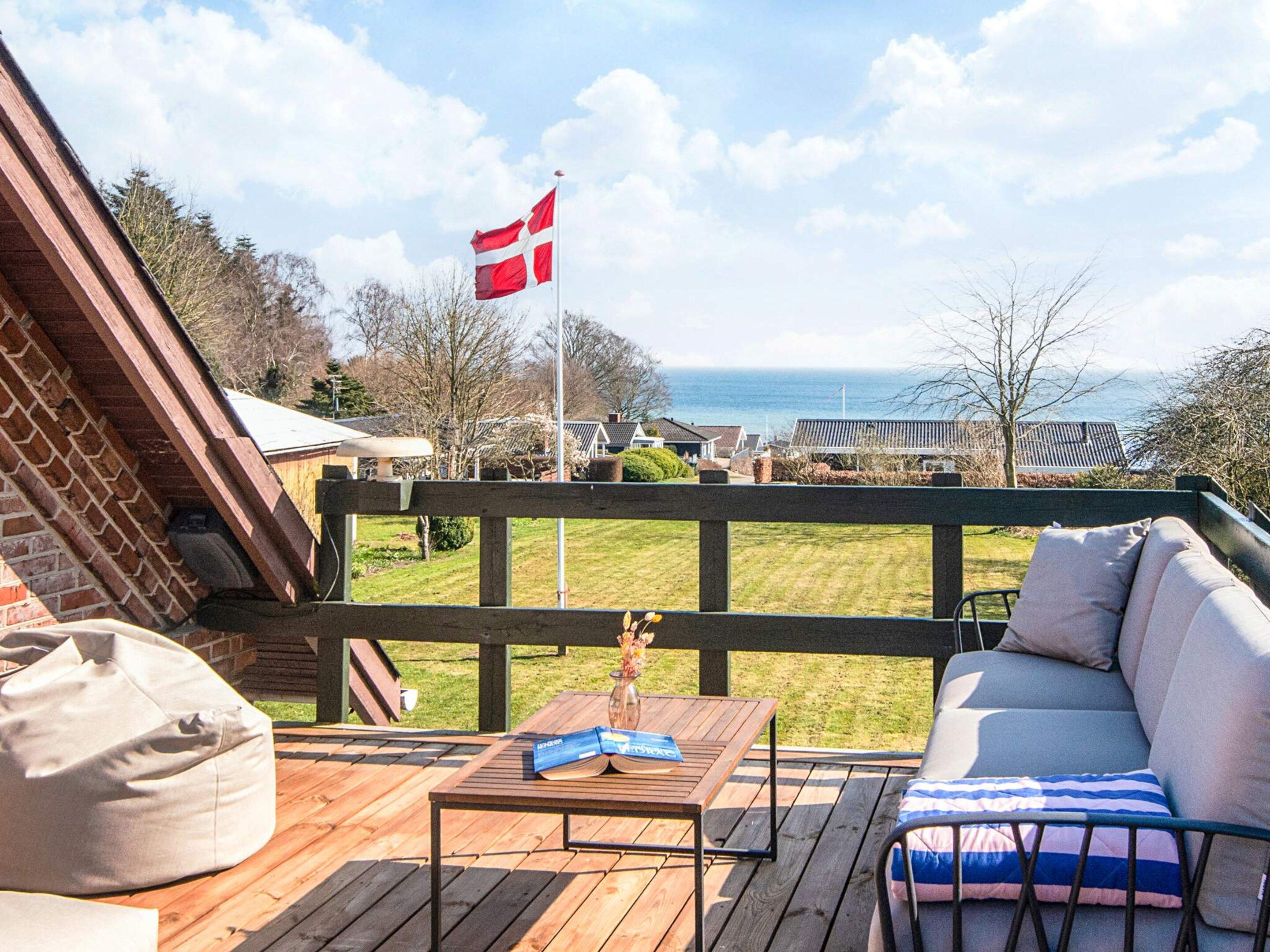 Terraza con vista al mar, una bandera y mobiliario exterior.