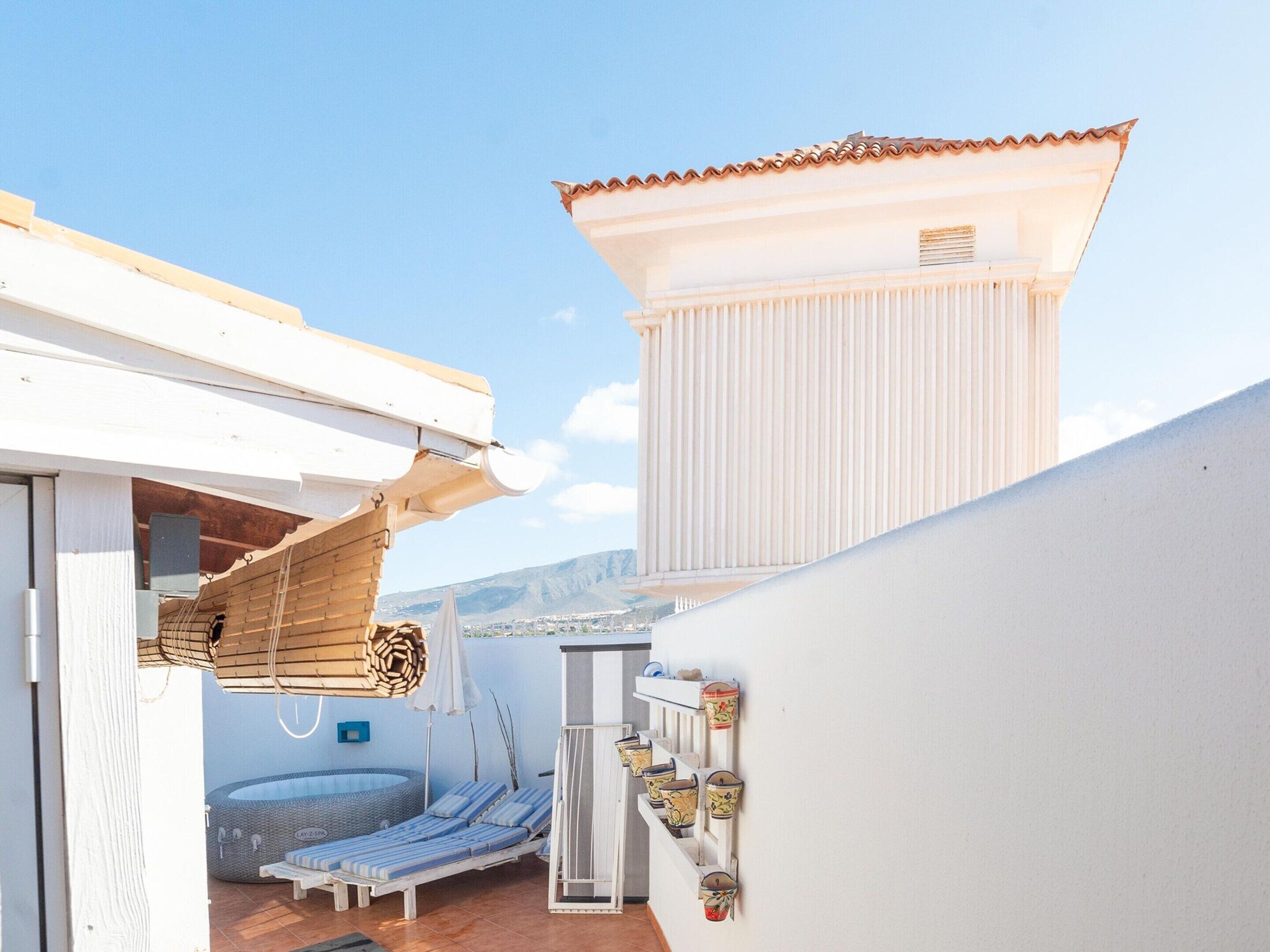 A rooftop terrace with a pool, lounge chairs, and a small building structure.