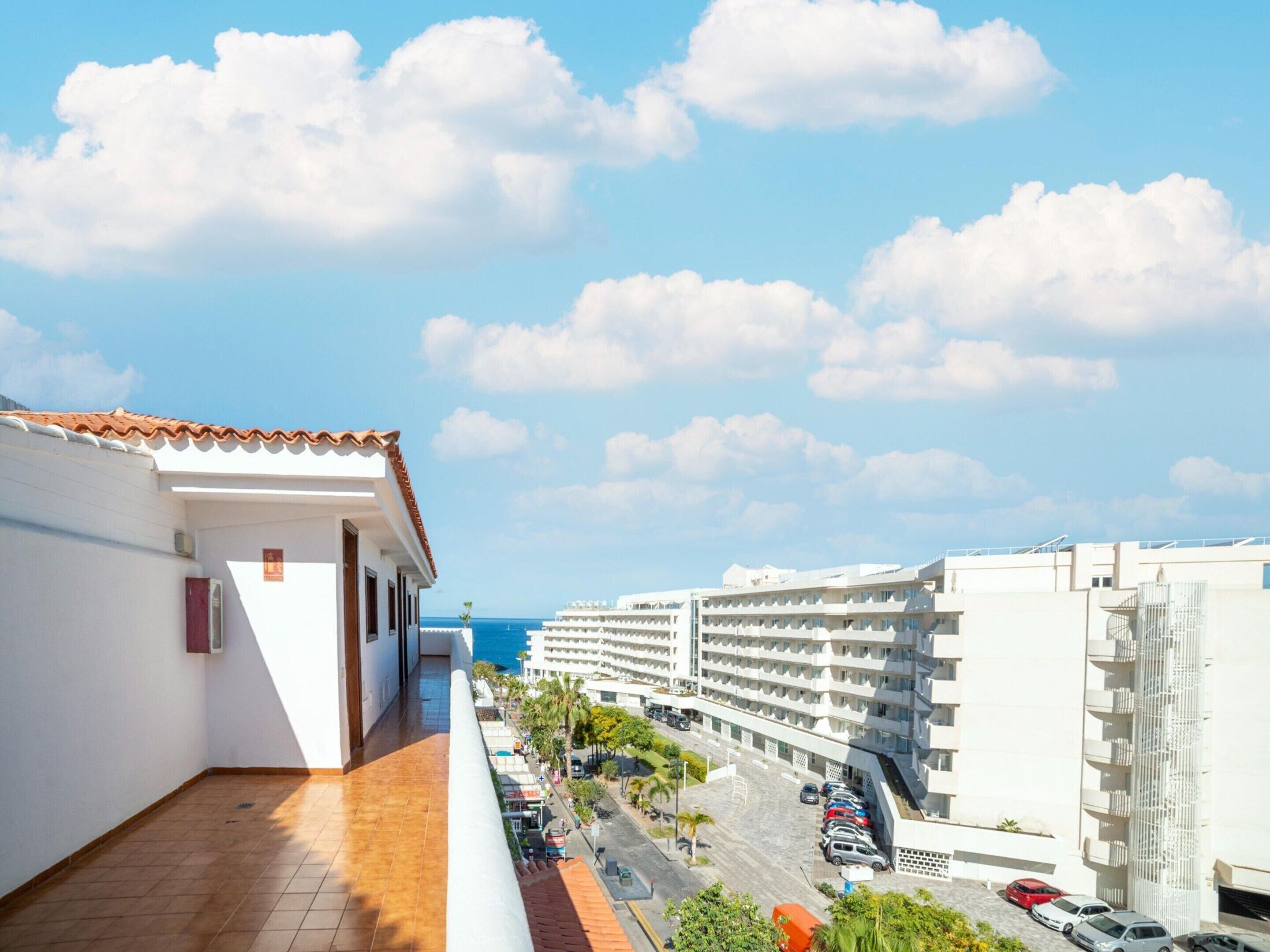 A hotel with a terrace overlooking a street and the sea.