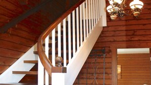 Eine Holztreppe mit weißen Balustraden und einer Kandelaberleuchte.
