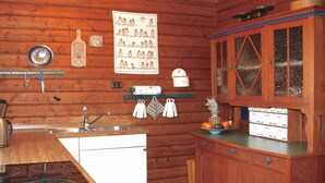Eine Küche mit Holzwänden, einem weißen Kühlschrank, einem Herd, einem Waschbecken und einem Holzkasten mit Glastüren.
