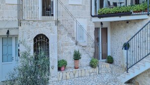 Un edificio de piedra con una escalera que conduce a un balcón con plantas en macetas.