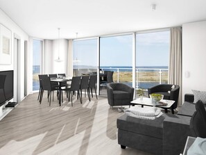 Een moderne woonkamer met een eethoek, grote ramen en uitzicht op zee.