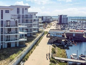 A coastal residential area with modern buildings, a marina, and a walkway. - Holiday Home in Wendtorf (Wendtorf)