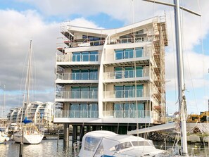A multi-story building with balconies, large windows, and a waterfront location. - Holiday Home in Wendtorf (Wendtorf)