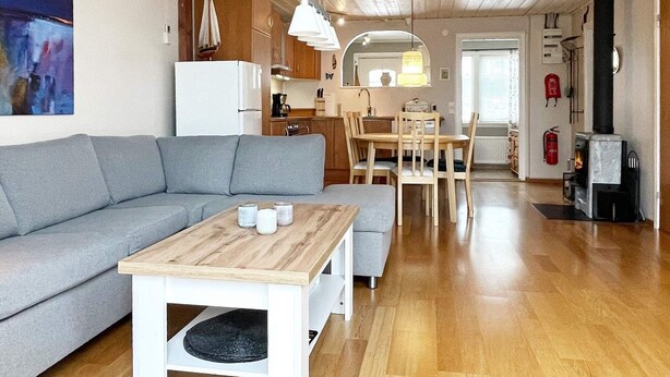 Un salon moderne avec un canapé gris, une table basse en bois et un coin repas comprenant une table et des chaises.