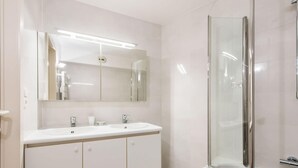 A modern bathroom with a double sink vanity, a large mirror, and a glass-enclosed shower. - La Boheme 204 G1 Stylish Apartment in Koksijde (Koksijde)