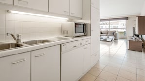 A modern kitchen with white cabinets, a built-in microwave, and a stainless steel sink. - La Boheme 204 G1 Stylish Apartment in Koksijde (Koksijde)