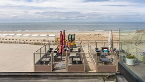 Une terrasse au bord de la plage, avec des sièges en plein air et une vue sur la mer.