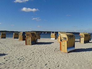 Beach huts numbered 365, 233, 066, 399, and 320 on a sandy beach with a clear sky and water in the background. - Holiday Apartment Kunsthues Laboe (Laboe)