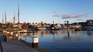 Un puerto deportivo con barcos amarrados, cielo despejado y edificios al fondo.