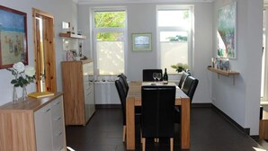 Un comedor moderno con una mesa de madera, sillas negras y una cocina al fondo.