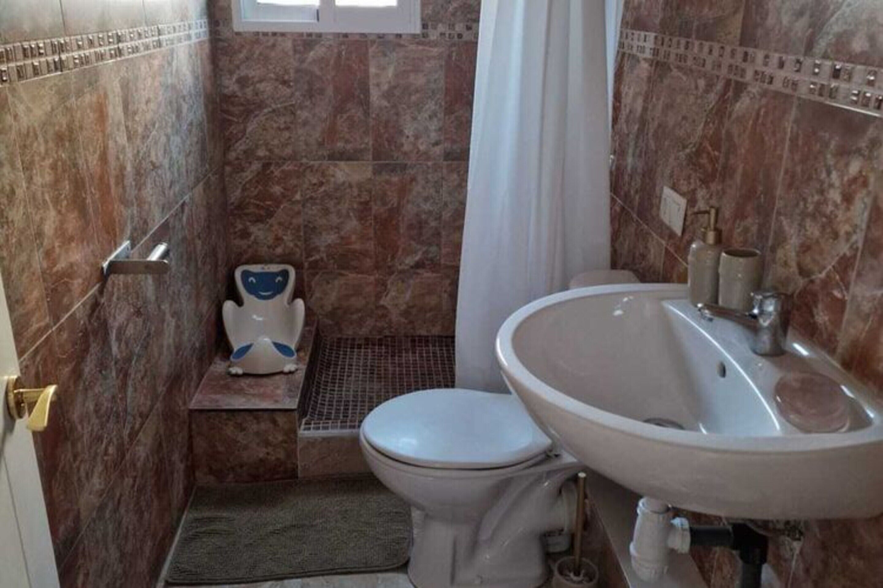 A bathroom with a toilet, a sink, and a shower area.