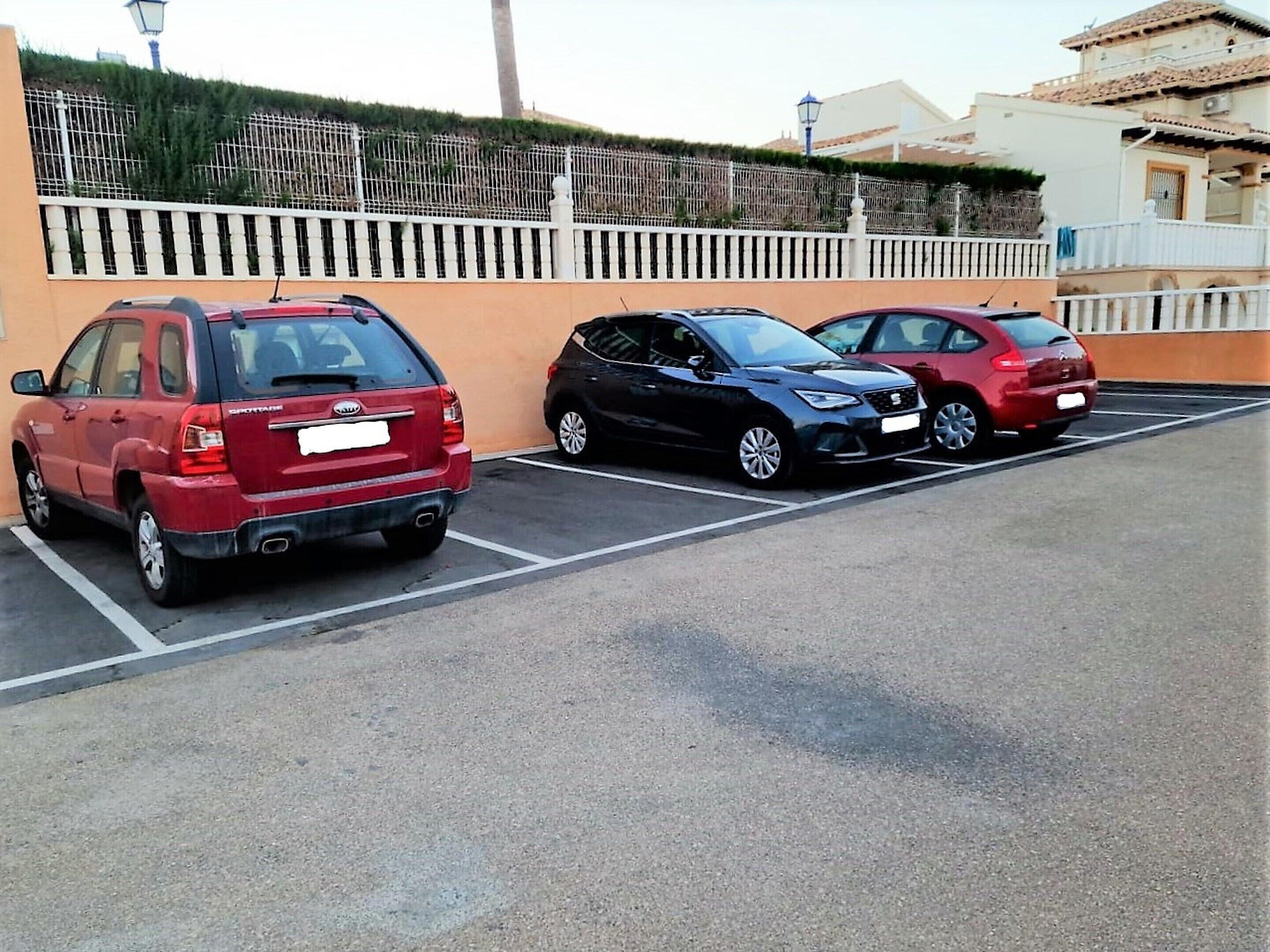 A parking lot with three cars parked in designated spaces.