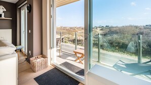 Una habitación moderna con un amplio ventanal corredero que da a una terraza exterior.