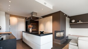 Una cocina moderna con una isla central, horno empotrado y chimenea.