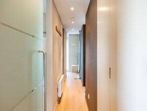 Een moderne hal met een radiator, een houten vloer en een glazen deur links.