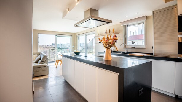 Una cocina moderna con una isla grande, vistas de la ciudad y un comedor con sofá y mesa.