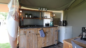 Una cocina compacta con encimera de madera, un refrigerador pequeño y una cafetera.