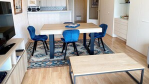 Une cuisine moderne avec des meubles blancs, une table à manger en bois et des chaises bleues.