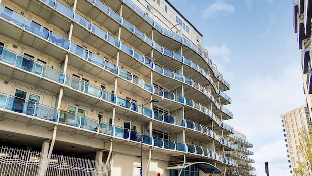 A multi-story residential building with balconies, a gated entrance, and a parking area. - Stylish Stay by the Seafront (Middelkerke)