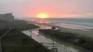 A coastal sunset view with a road leading to the beach, a construction site, and a building in the distance. - Stylish Stay by the Seafront (Middelkerke)