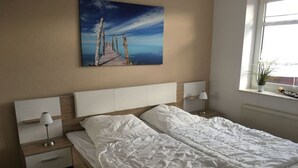 Een slaapkamer met een groot bed, twee nachtkastjes, een raam met uitzicht en een schilderij aan de muur.