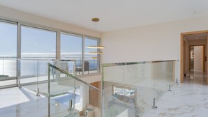 A spacious interior with large windows offering a view of the sea, a glass railing, and a modern design.