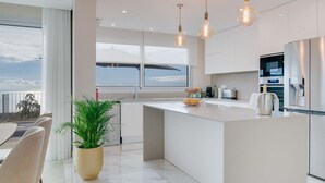 A modern kitchen with a large island, stainless steel appliances, and pendant lighting.