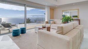 A modern living room with a large glass window overlooking a scenic ocean view.