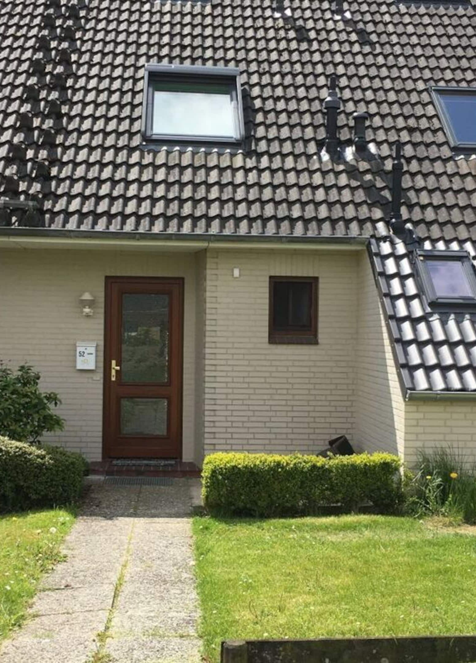 Ein Wohnhaus mit Ziegeldach, einer Haustür und einem kleinen Fenster.