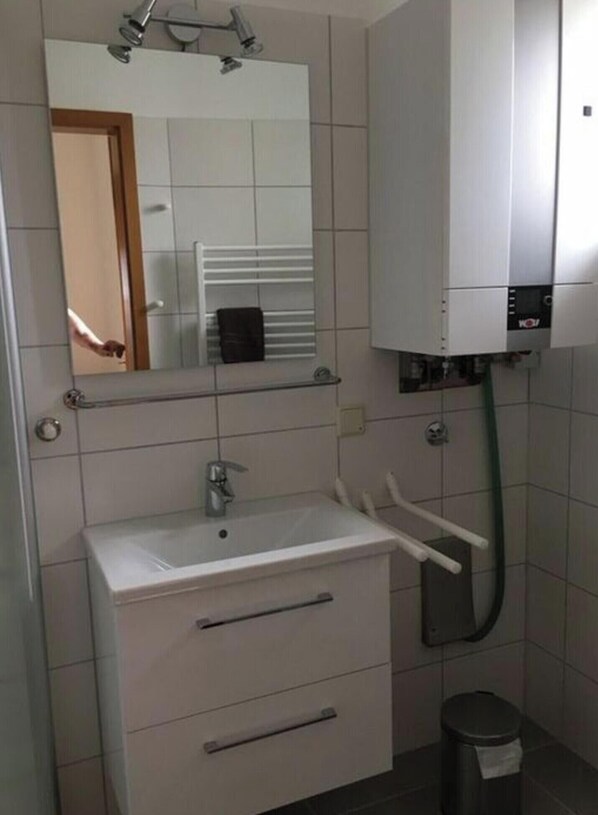 Casa de banho com lavatório branco, espelho, porta-toalhas e sanita.