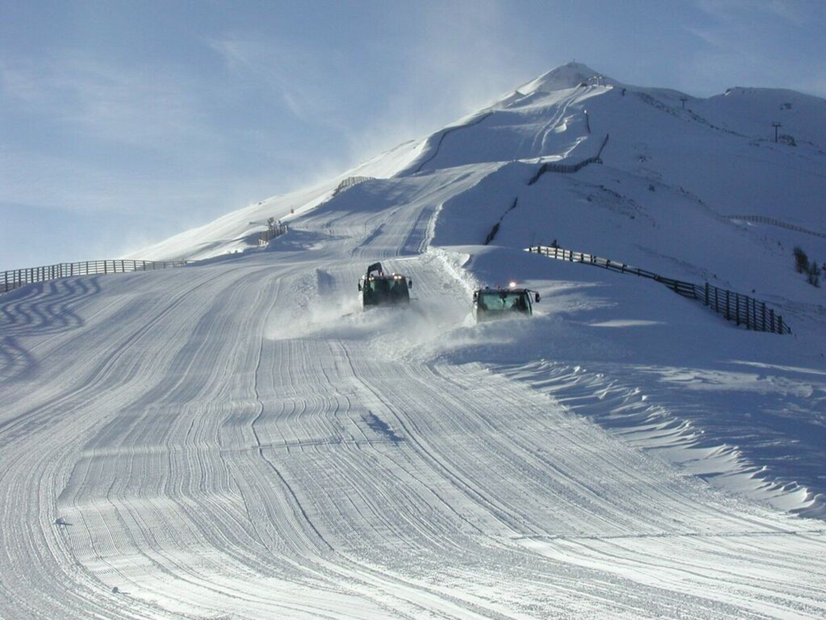 A snow-covered mountain road with two vehicles driving.