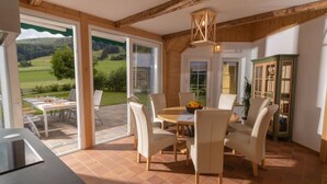 A modern kitchen with a large window, a dining area with a round table, and a view of a green landscape. - Chalet Yuma 4 People (Mauterndorf)