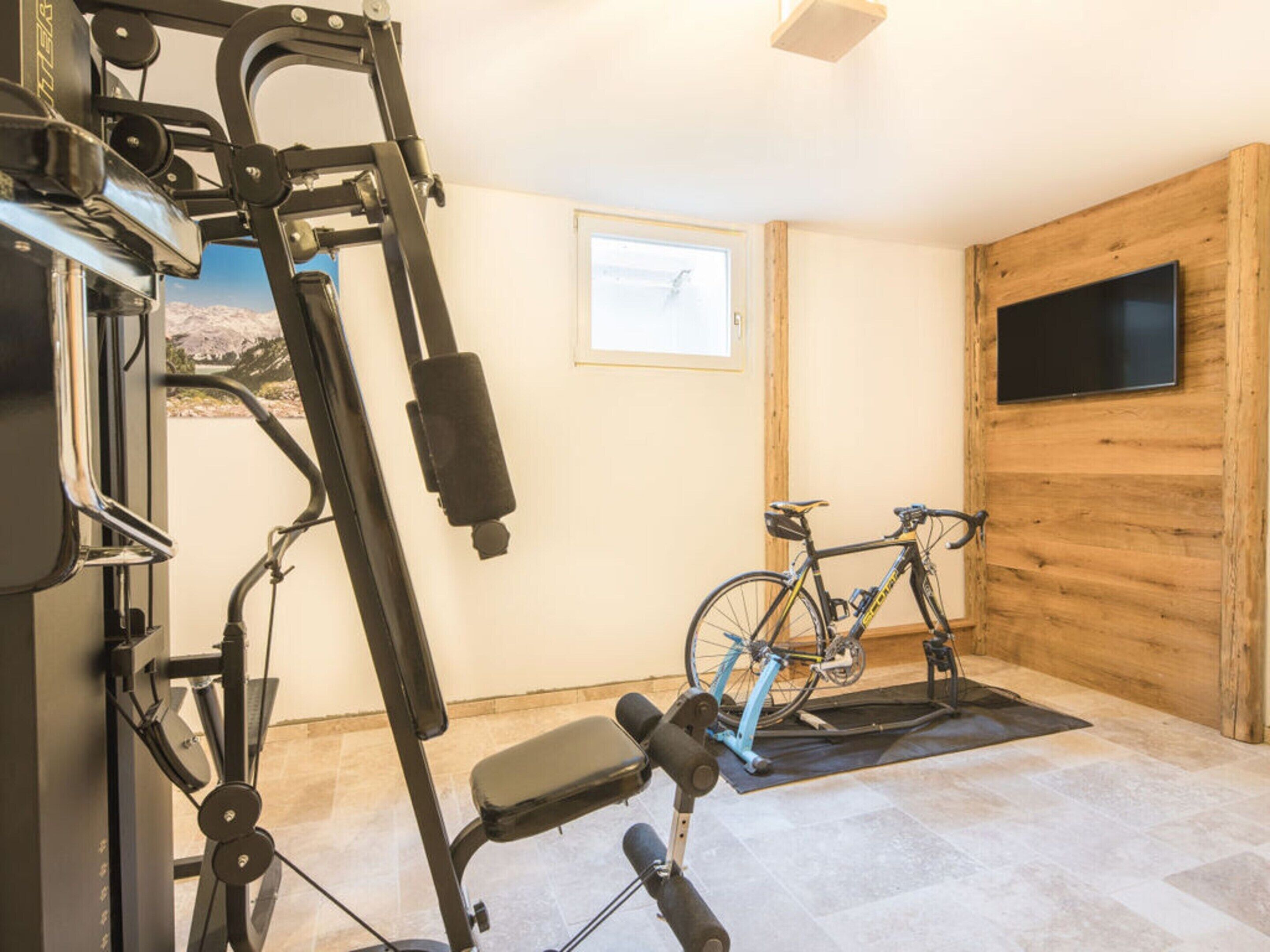 A gym with exercise equipment, a bicycle, and a TV mounted on a wooden wall.