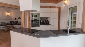 A modern kitchen with white cabinetry, a built-in oven, and a central island with a sink. - Chalet Yuma 4 People (Mauterndorf)