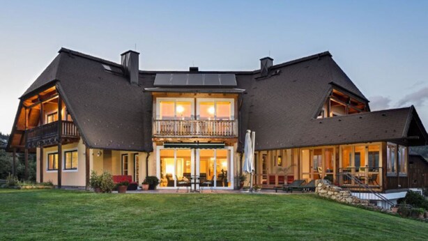 A large, two-story house with a balcony on the upper floor, a covered patio area, and a well-maintained lawn. - Chalet Yuma 4 People (Mauterndorf)