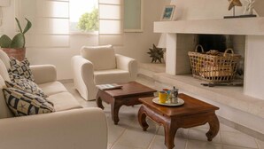 Uma sala de estar com lareira, um sofá, uma mesa de centro e uma janela com persianas.