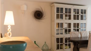 Um quarto com um armário branco com portas de vidro, uma tigela azul sobre uma mesa, um abajur e um ninho fixado na parede.