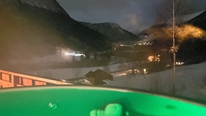 A nighttime view from a hot tub overlooking a snowy landscape with distant buildings. - 8 Person Holiday Home in Valldal (Fjord)